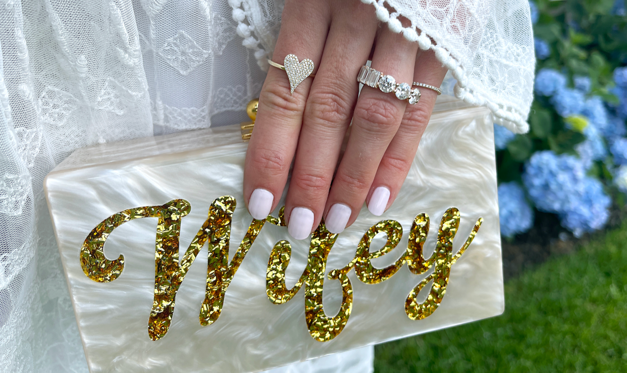 Woman holding clutch bag which says "Wifey"