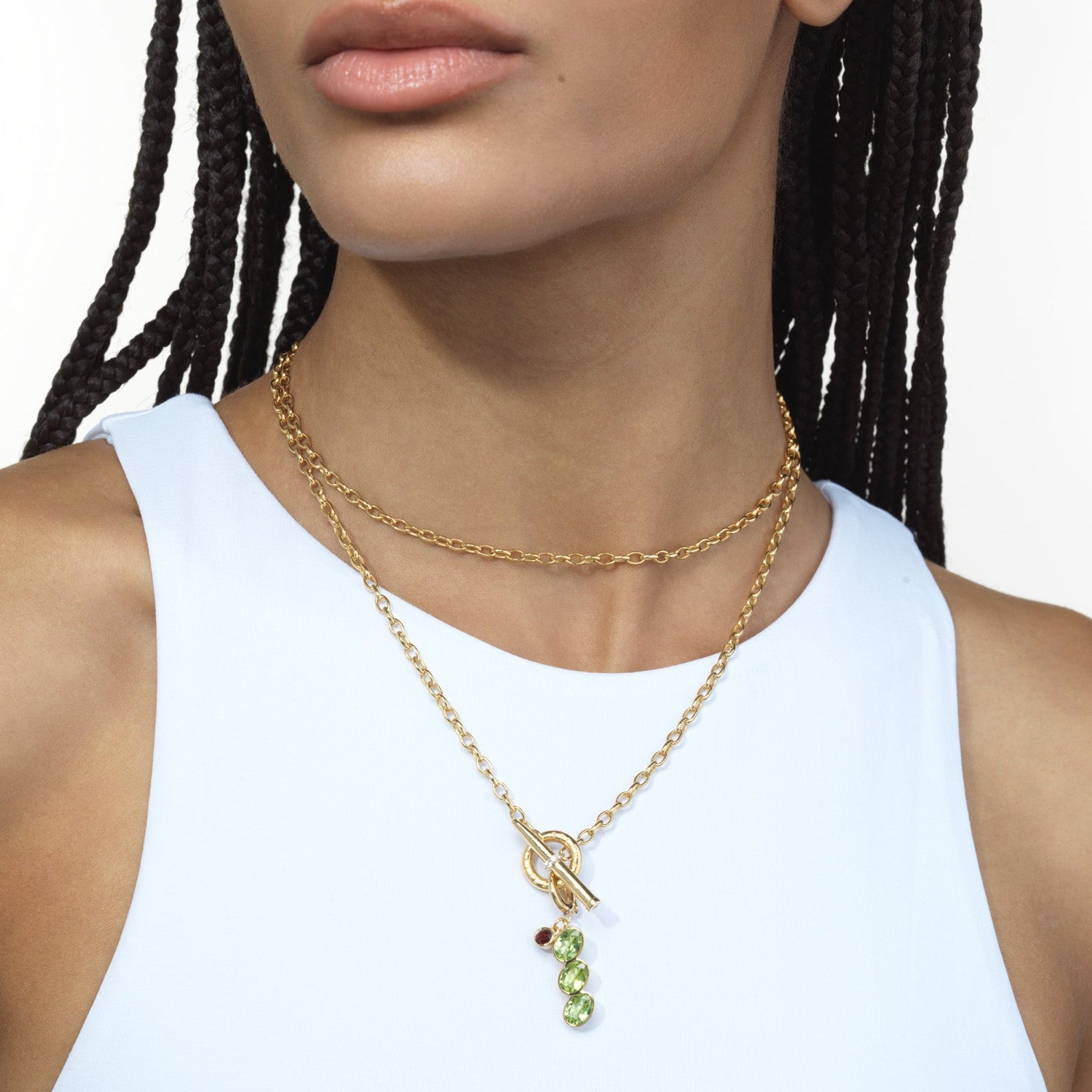 Woman wearing a gold chain necklace with an olive charm pendant