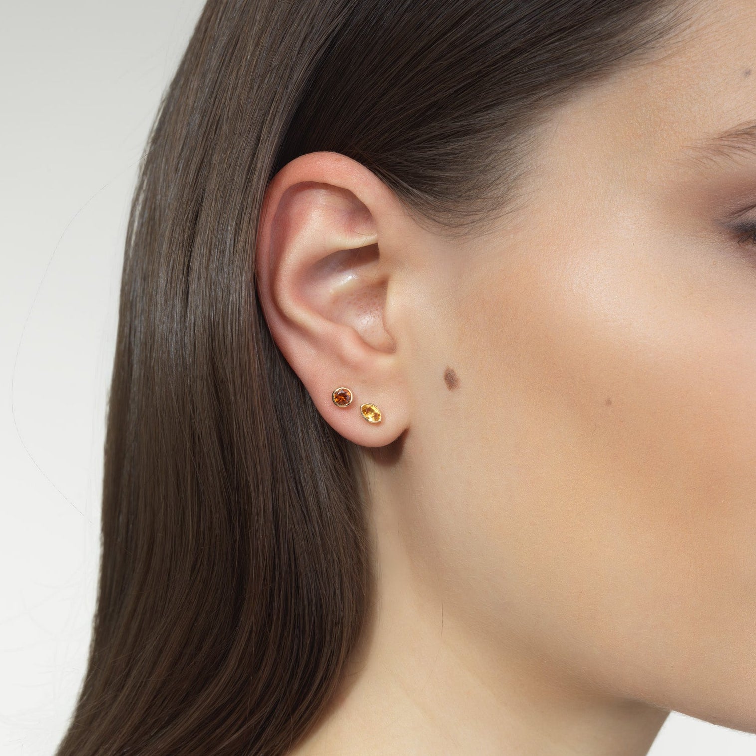 woman wearing orange gemstone studs and lemon gemstone studs