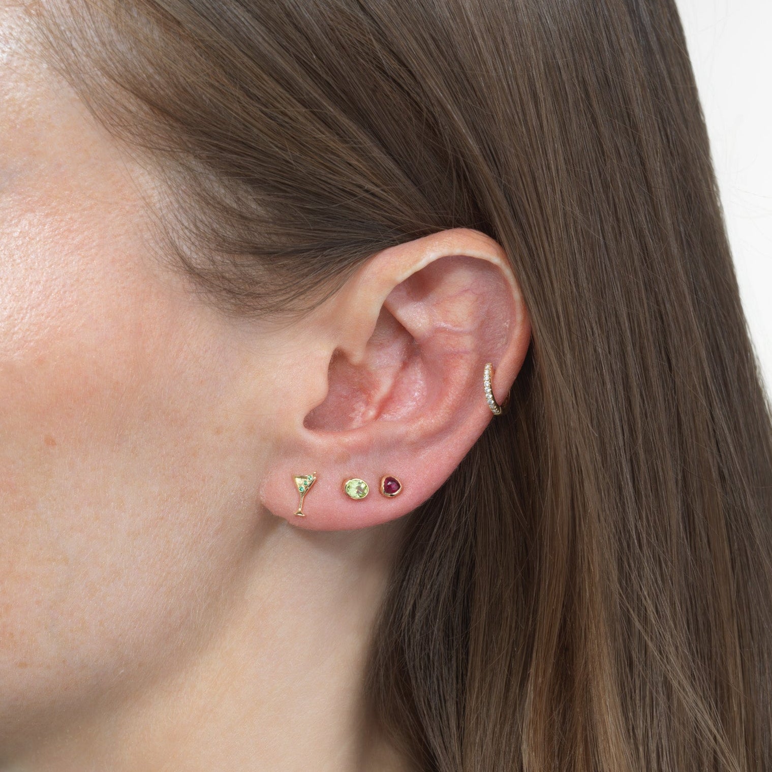 woman wearing martini glass stud, green and red gemstone studs